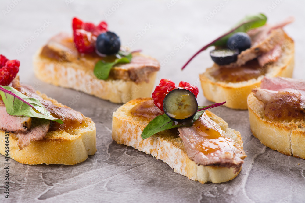 Bruschetta sandwiches with duck meat and berries