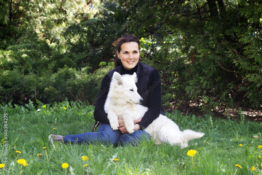 Woman and white sheepdog on green grass