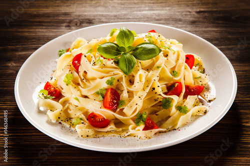 Tableau sur toile Pasta with tomatoes on wooden table