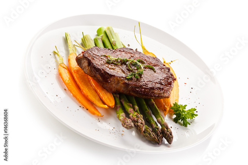 Grilled beefsteak with asparagus and carrot on white background