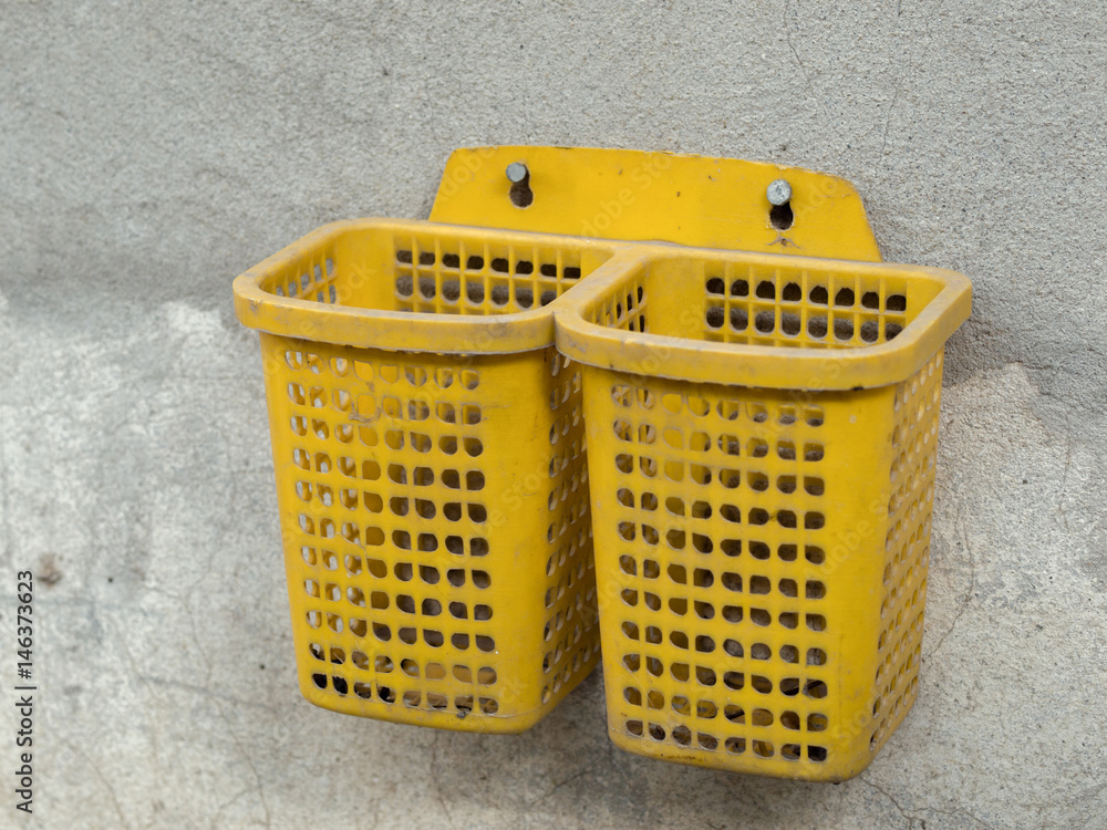 Fototapeta premium COLOR PHOTO OF PLASTIC BASKET SCREWED ON CONCRETE WALL