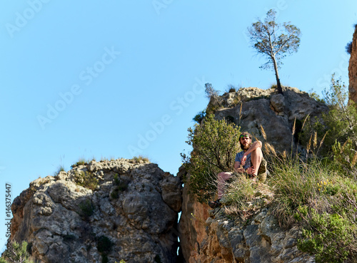 Bearded man traveler sitting on a mountain edge