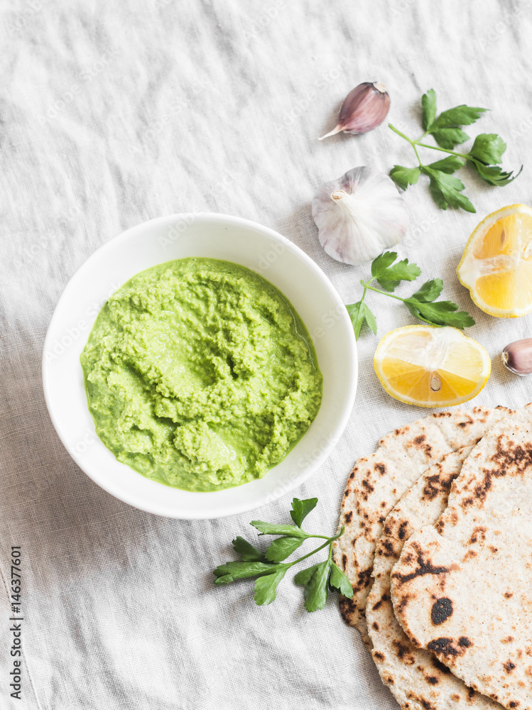 Green avocado dip and gluten free flatbread on a light background, top view. Healthy vegetarian snack Green avocado dip and gluten free flatbread on a light background, top view. Healthy vegetarian snack