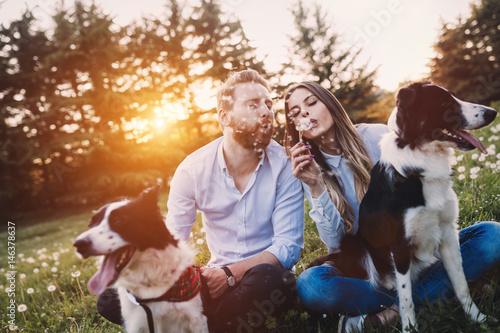 Canvas Print Romantic couple in love walking dogs in nature and smiling