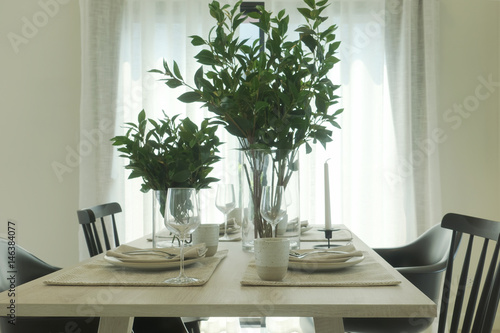 Simply dining table with vase of green leaves at the center