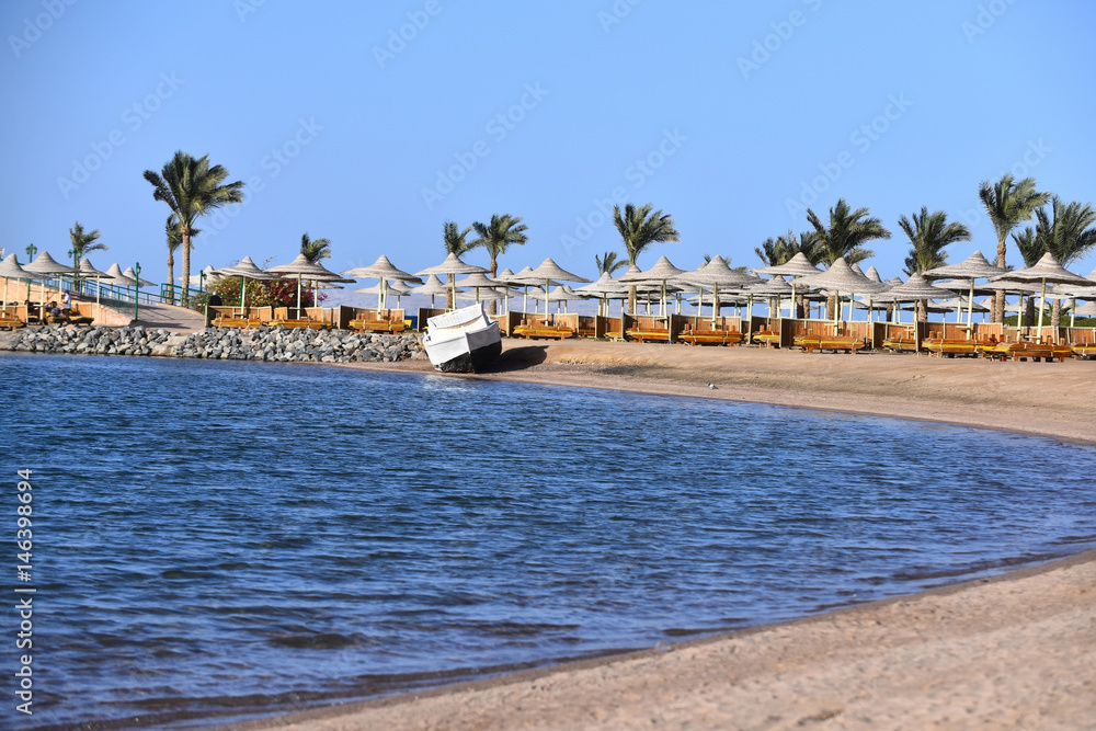 Obraz premium Tropical sandy beach with white motor boat on blue sea