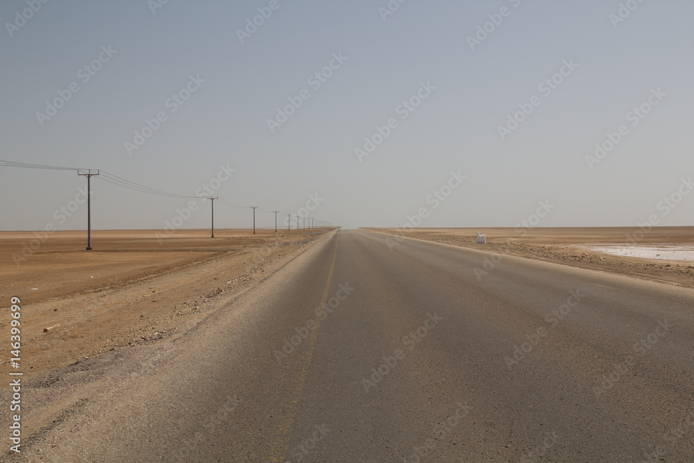 Endless road in Oman leading through a salt flat