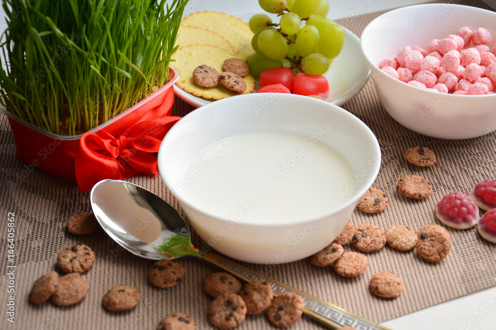 A plate of milk with a spoon, grapes and crispy balls for breakfast A plate of milk with a spoon, grapes and crispy balls for breakfast