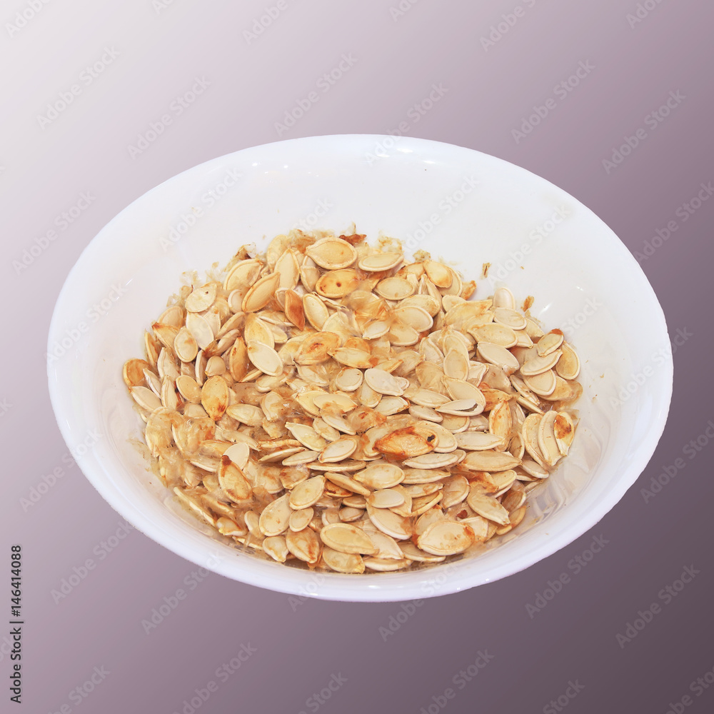 Plate with dried white sunflower seeds isolated on a gray background. Plate with dried white sunflower seeds isolated on a gray background.
