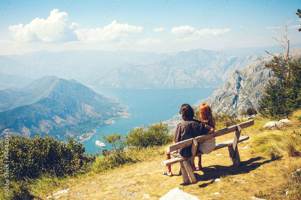 A guy with a girl is sitting on a bench in Kotor Bay. Happy family of four walking in the mountains. Family concept. Family trip.