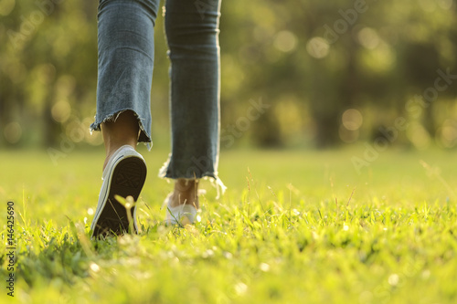 white sneaker jeans walking on green grass with sunset light