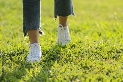 white sneaker jeans walking on green grass with sunset light