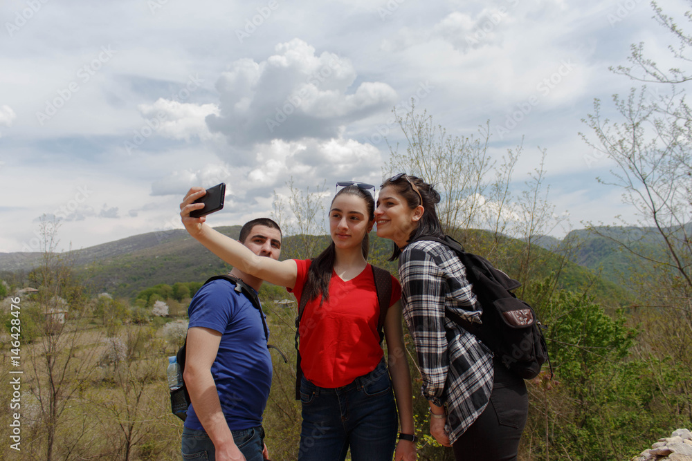 Group of friends are hiking in mountain. Three young people walking through countryside.