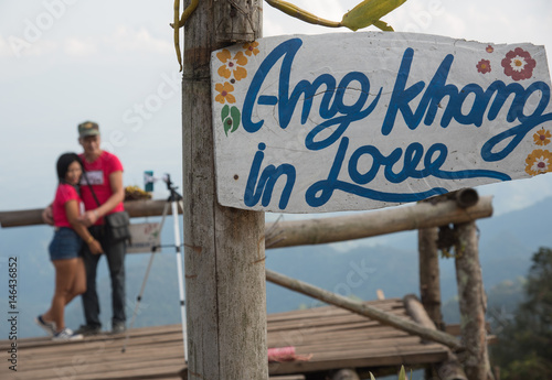 A sign at Doi Ang Khang with a woman in the background. photo