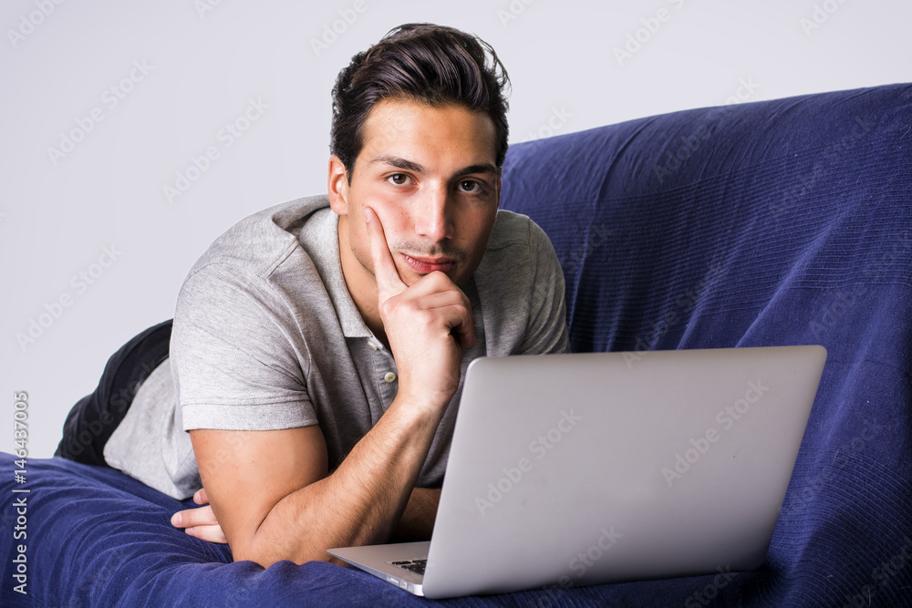 Young attractive man working with computer while sitting on couch, on white background Young attractive man working with computer while sitting on couch, on white background