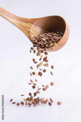 Spoon of lentil falling on a white background