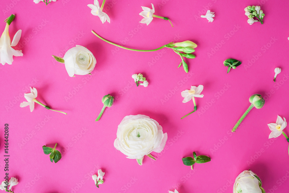 Fototapeta premium Floral pattern of white ranunculus, snapdragon and leaves on pink background. Flat lay, top view. Summer background.