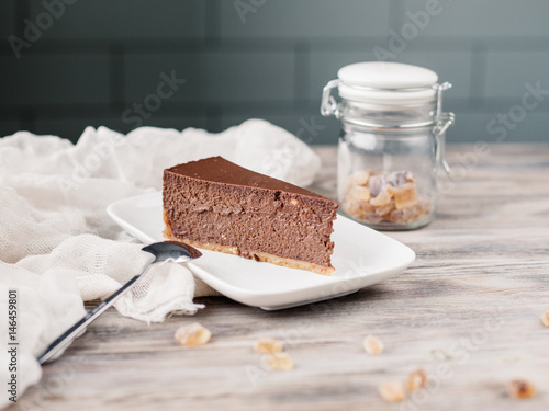 Кусок торта чизкейка на тарелке, деревянный фон. A slice of a chocolate cheese cake on a wooden background with some cane sugar cubes around. Low depth.  photo