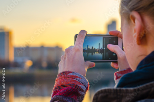 Young woman takes pictures of the city on a smartphone photo