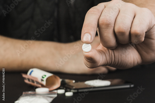 A drug addict or a drug dealer holding a pill with the drug.