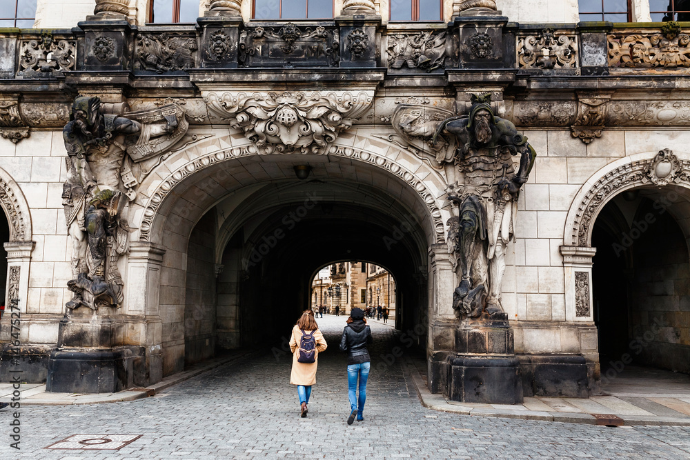 Two female tourists pass through an arch decorated with ancient statues of Saxon warriors