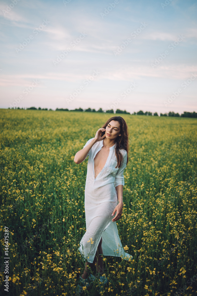 Fototapeta premium Girl walking in the field at sunset