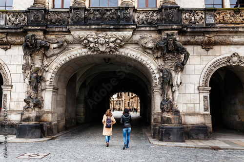 Two female tourists pass through an arch decorated with ancient statues of Saxon warriors