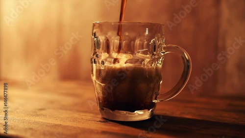 Pouring dark beer in british dimpled glass pint mug on bar table
