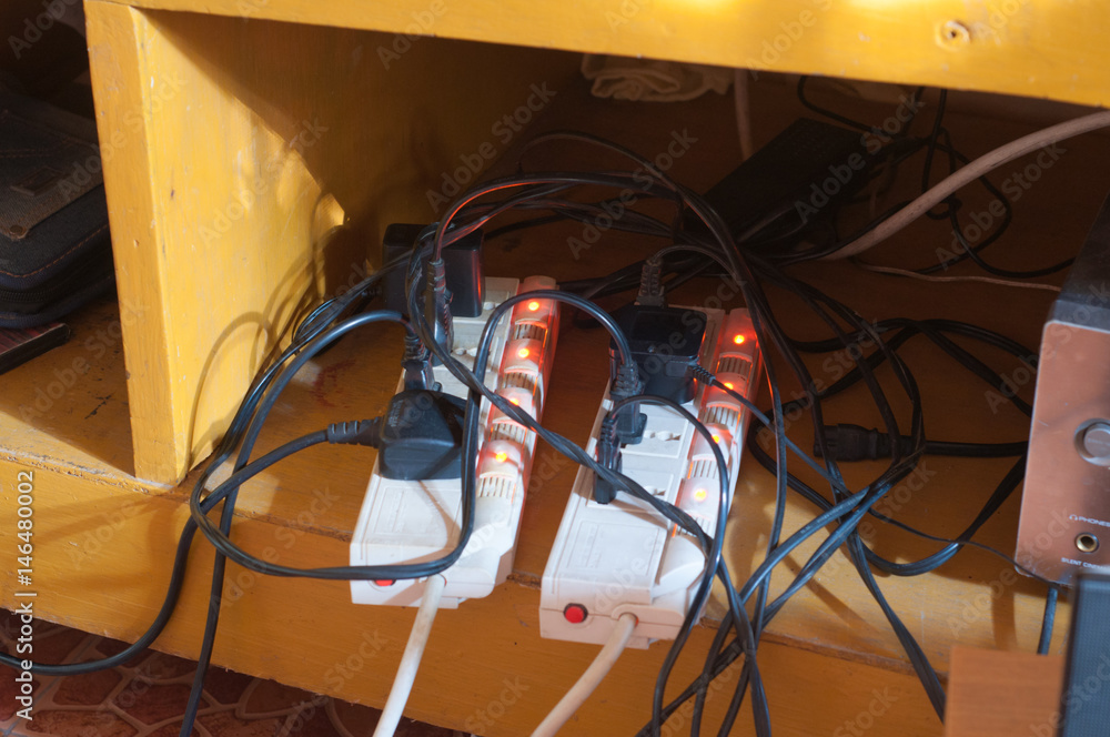 Two AC extension all occupied slots. Cause of short circuit. Electric, danger in electricity, appliance, cords, wires, fire, dangerous. A messy power lines Two AC extension all occupied slots. Cause of short circuit. Electric, danger in electricity, appliance, cords, wires, fire, dangerous. A messy power lines