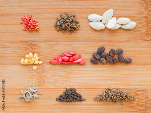 Different seeds set on wooden board background. Tomatos, carrot, zucchini, sweet pepper, cucumber, watermelon, cherry tomatos, lettuce and parsley.