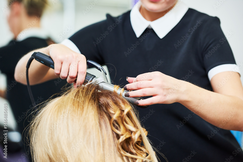 Naklejka premium hairdo in beauty salon. hairdresser making coiffure with curl to wonam