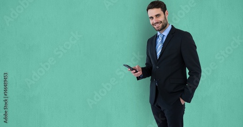 Confident businessman using mobile phone over green background photo