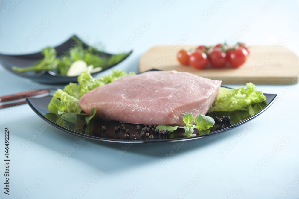 Raw pork on black lettuce and lettuce, portion, schnitzel, cutlet Raw pork on black lettuce and lettuce, portion, schnitzel, cutlet