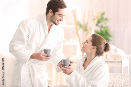Young happy couple drinking tea in spa salon