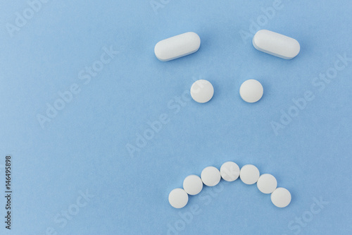 upset face made by pills on blue background