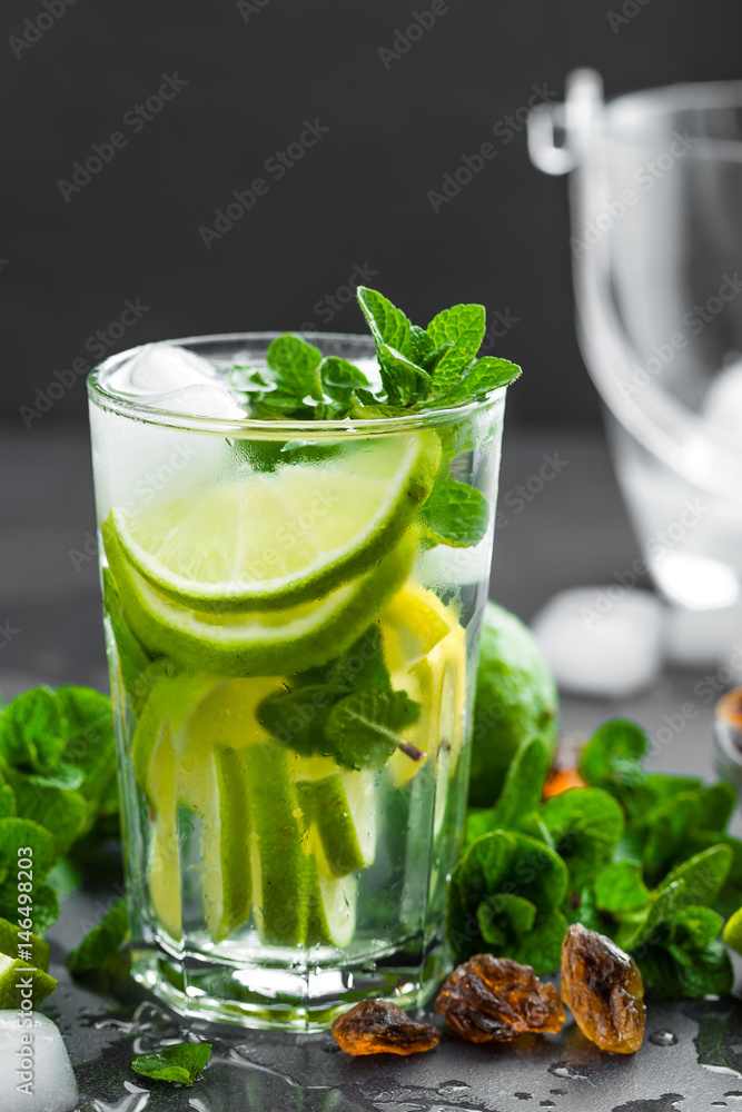 Refreshing mint cocktail mojito with rum and lime, cold drink or beverage with ice on black background Refreshing mint cocktail mojito with rum and lime, cold drink or beverage with ice on black background