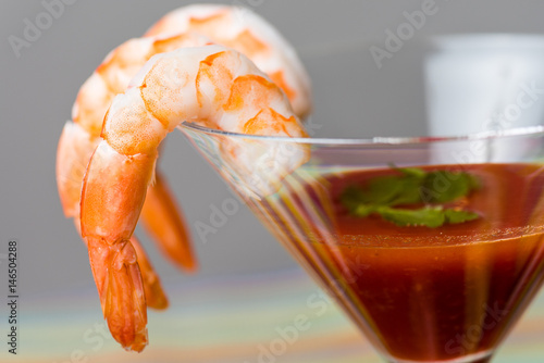 Shrimp cocktail with sauce served in a martini glass and garnished with parsley. photo