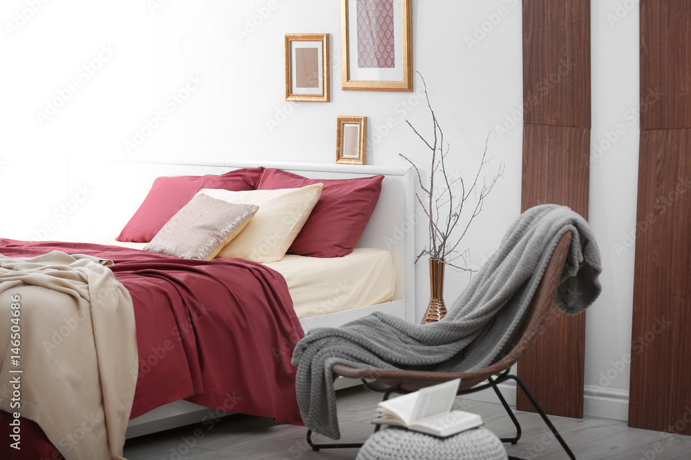 Fotografie Comfortable bed with burgundy bedding in modern interior design