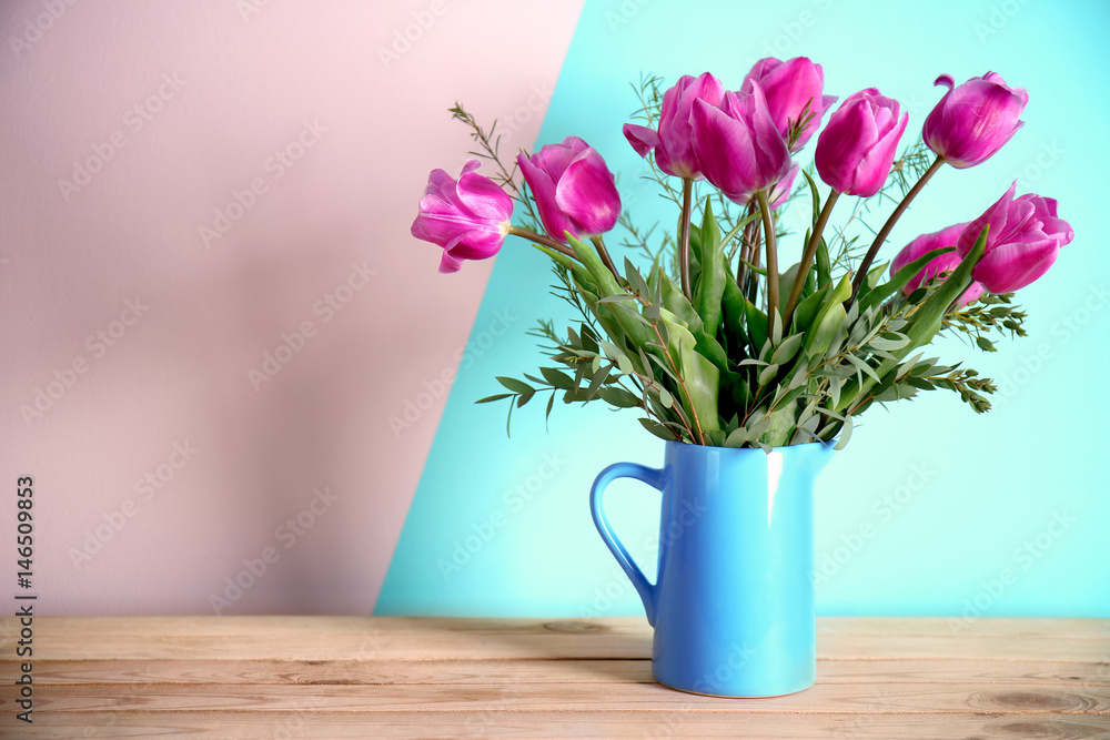 Fototapeta premium Jug with beautiful bouquet of spring flowers on wooden table