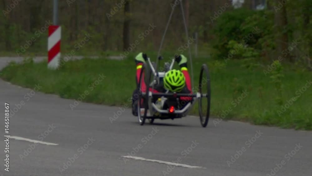 Wide shot of a recumbent biker riding on a dike in Holland. The city contours are visible in the background Wide shot of a recumbent biker riding on a dike in Holland. The city contours are visible in the background