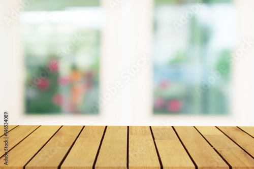 Perspective wooden table on top over blur window background, can be used mock up for montage products display or design layout.