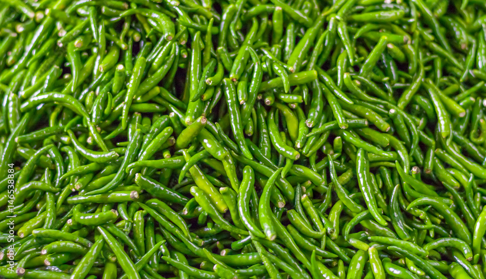 Pile of fresh green chilli peppers texture. Raw food background. Close up. Traditional vegetable market in Bangkok, Thailand. Pile of fresh green chilli peppers texture. Raw food background. Close up. Traditional vegetable market in Bangkok, Thailand.