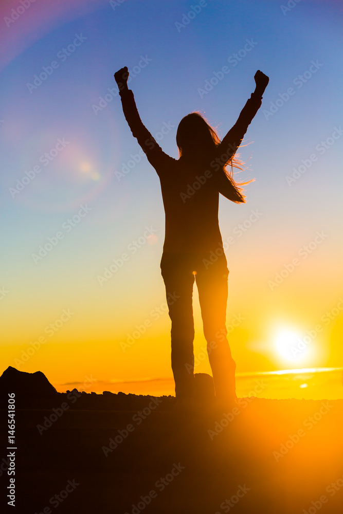 Winner woman winning with open arms in success of reaching mountain top in sunset flare, goal challenge achievement. Sport and active healthy living concept.