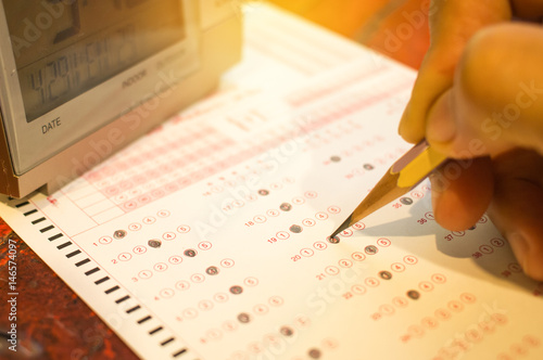 alarm digital clock on optical form standardized test with bubbled and a black pencil examination for answer sheet, education concept