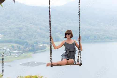 Sexy young aldy swinging over the precipice on the magic tropical Bali island, Indonesia.