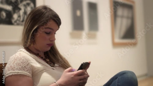 Bored attractive woman sitting in museum art gallery waiting for lame date to be over photo