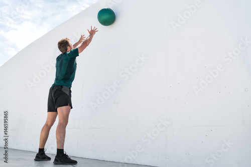 Canvas Print Strength training fit man cross training throwing medicine ball on gym wall at fitness centre