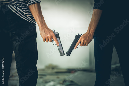 Two Robbers holding a gun at abandoned building. Low key photo and selective focus. criminality concept.