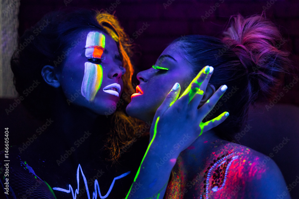 Sexy lesbian fashion models in uv neon light with fluorescent glowing Body  Art make-up kissing. Low key dark image. Soft focus image. Photos | Adobe  Stock