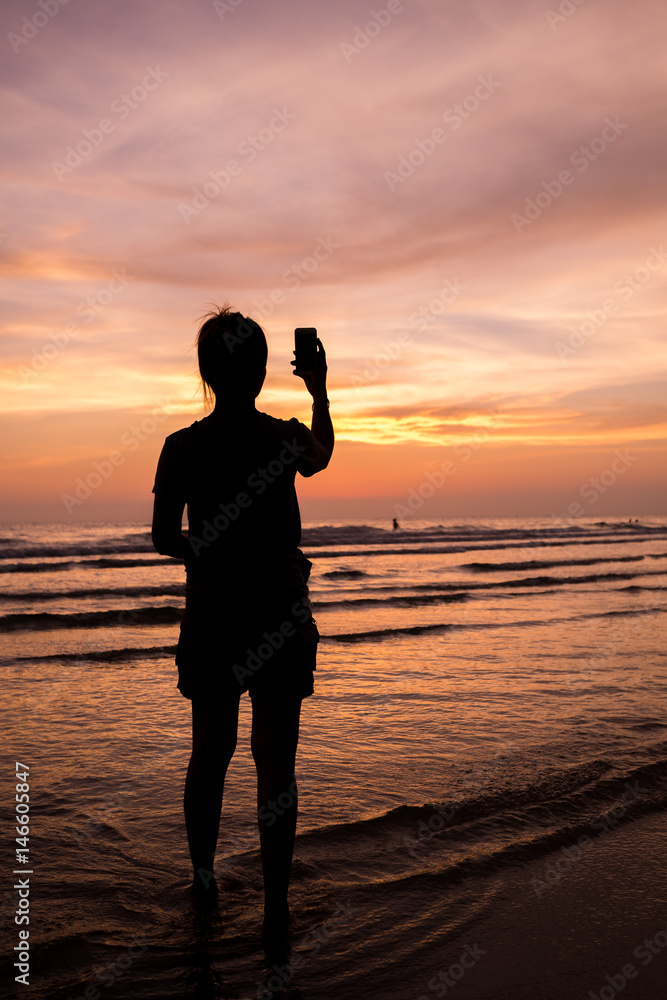 woman taken photo at sea sunset